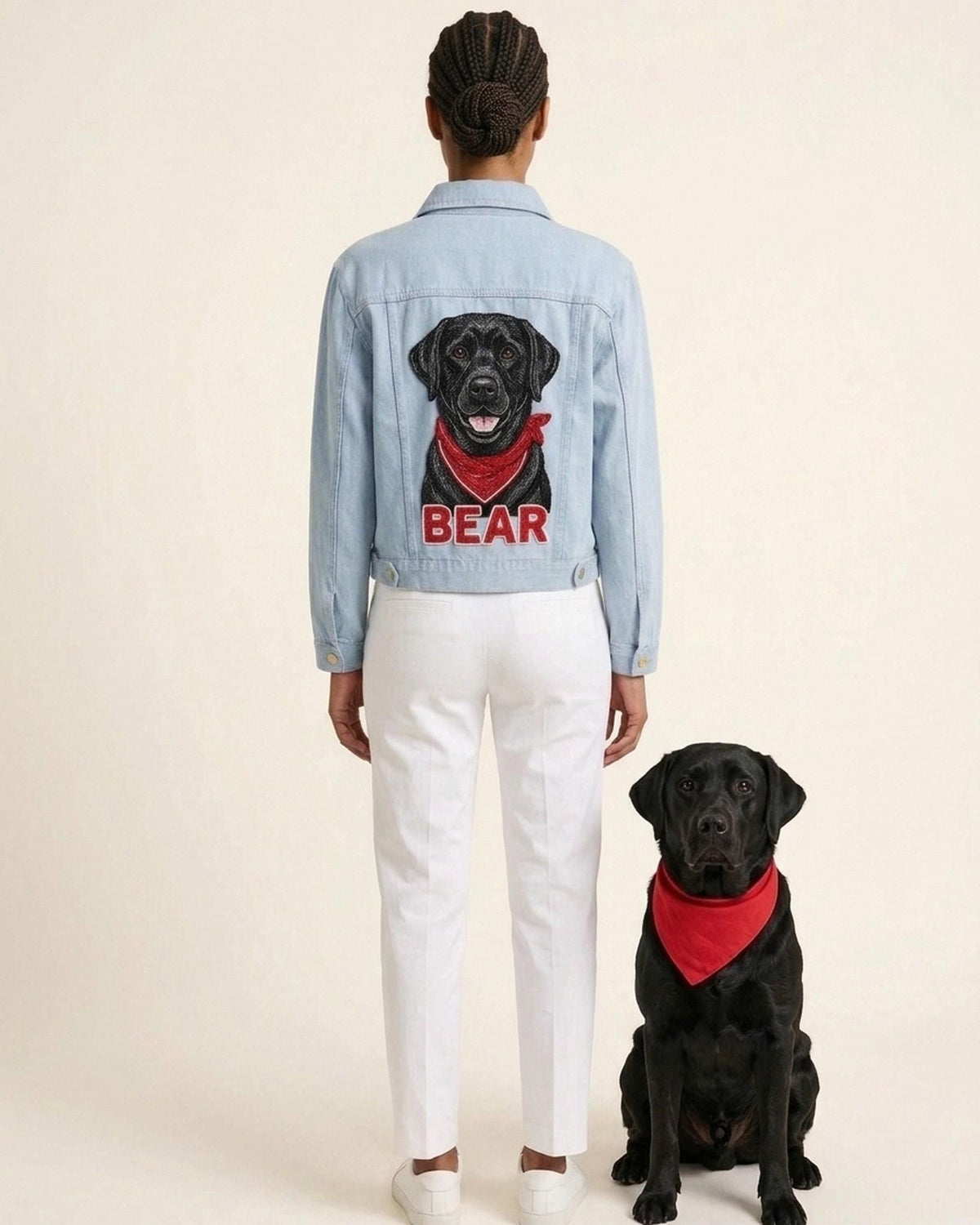 Owner wearing a hand-beaded black lab denim jacket, seen from the back, with her black labrador sitting beside her