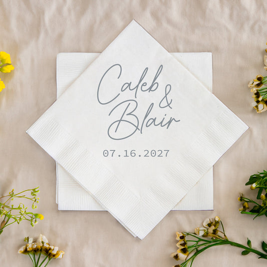 White napkin with 'Caleb & Blair 07.16.2027' text on a beige background with flowers.