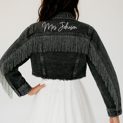 a woman wearing a jean jacket with fringes on it