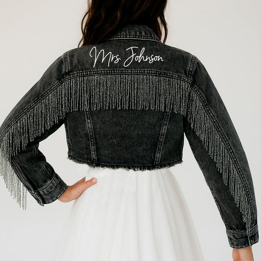 a woman wearing a jean jacket with fringes on it