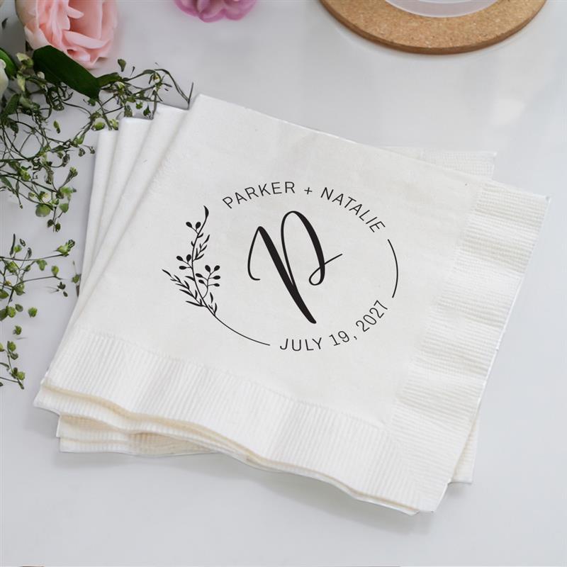 White napkins with personalized design on a light surface with flowers.