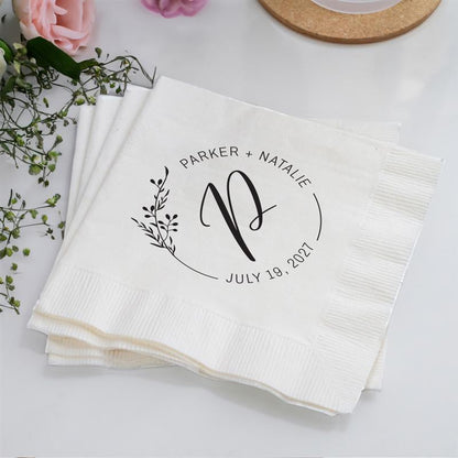 White napkins with personalized design on a light surface with flowers.