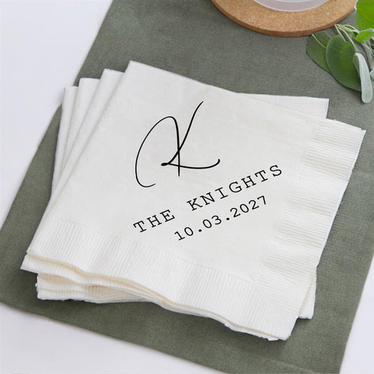 Stack of white napkins with personalized monogram and date on a green surface