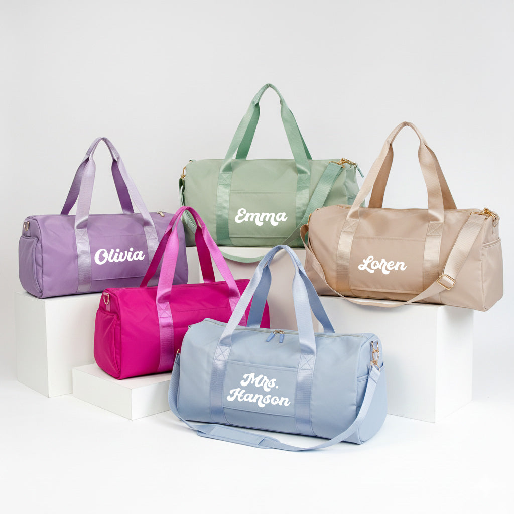 A collection of five colorful duffel bags with personalized names on them, arranged on a white background.