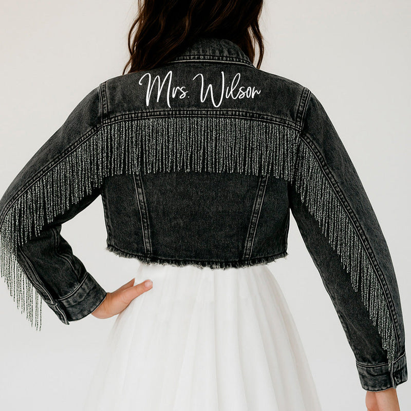 a woman wearing a jean jacket with fringes on it