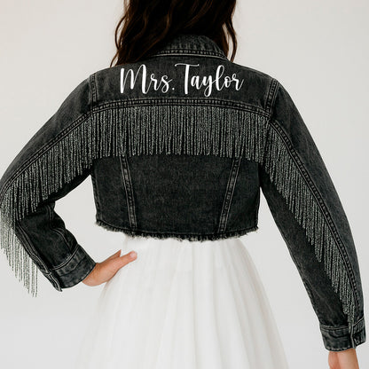 a woman wearing a black jean jacket with fringes