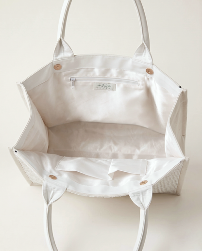 A white tote bag with a zipper and handles, open to reveal the interior.