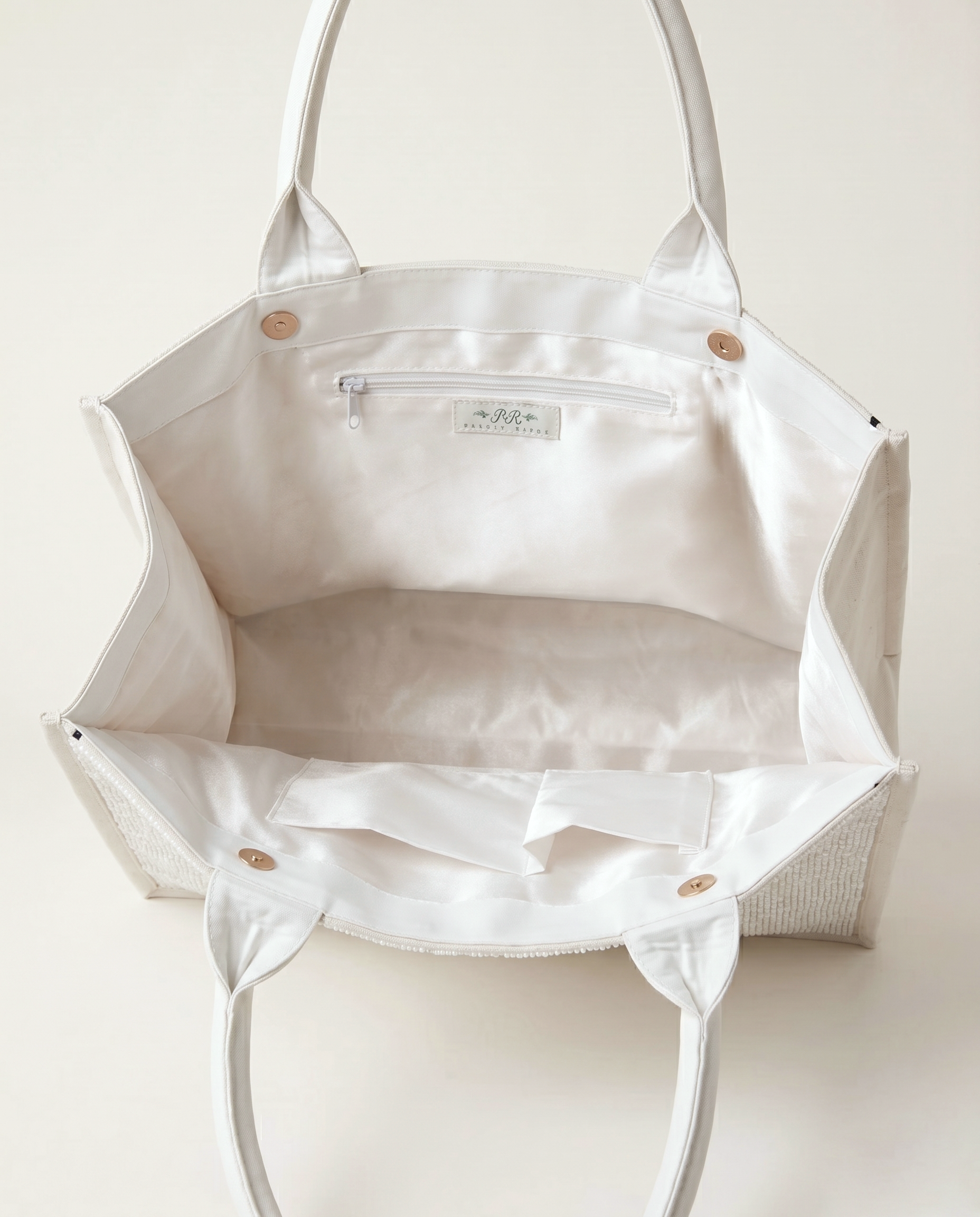 A white tote bag with a zipper and handles, open to reveal the interior.