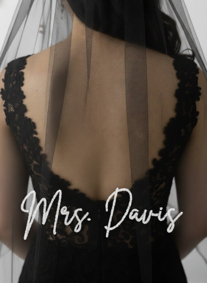 the back of a person wearing a black lace dress with a veil, and the name "Mrs. Davis" written on the back of the dress.