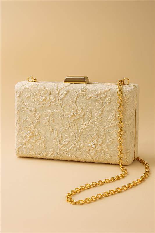 A white clutch purse with a gold chain strap is displayed against a light beige background.