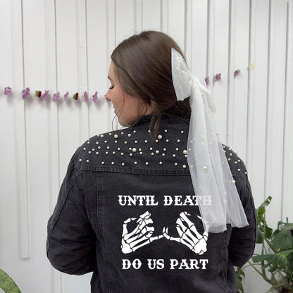 Person wearing a black jacket with skeleton hands and text, standing against a white wall with decorative elements.