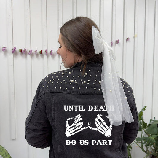 Person wearing a black jacket with skeleton hands and text, standing against a white wall with decorative elements.