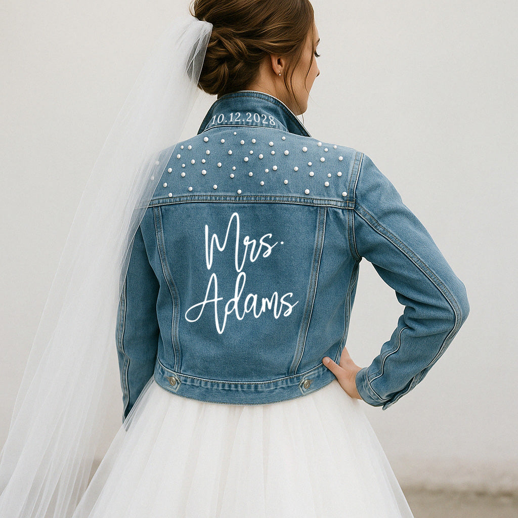 Woman wearing a blue denim jacket with 'Mrs. Adams' and a date on the back, standing against a plain background.