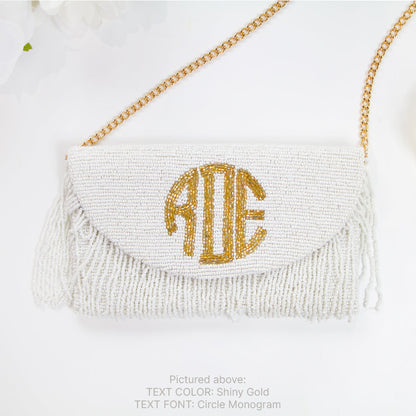 A white handbag with a gold monogram on the front, placed on a white background.