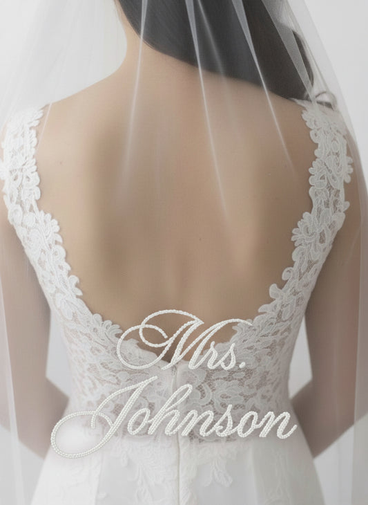 the back of a bride's dress with the name "Mrs. Johnson" embroidered on it.