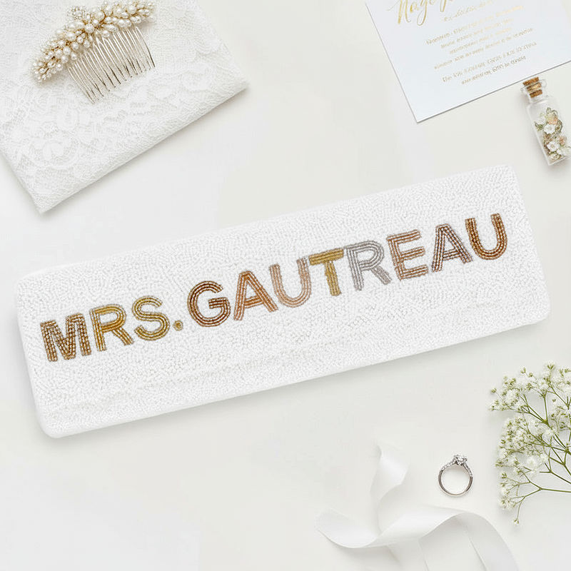 a white towel with the name "Mrs. Gautreau" printed on it, along with some decorative elements such as a hairbrush, a small vase, and a ring.