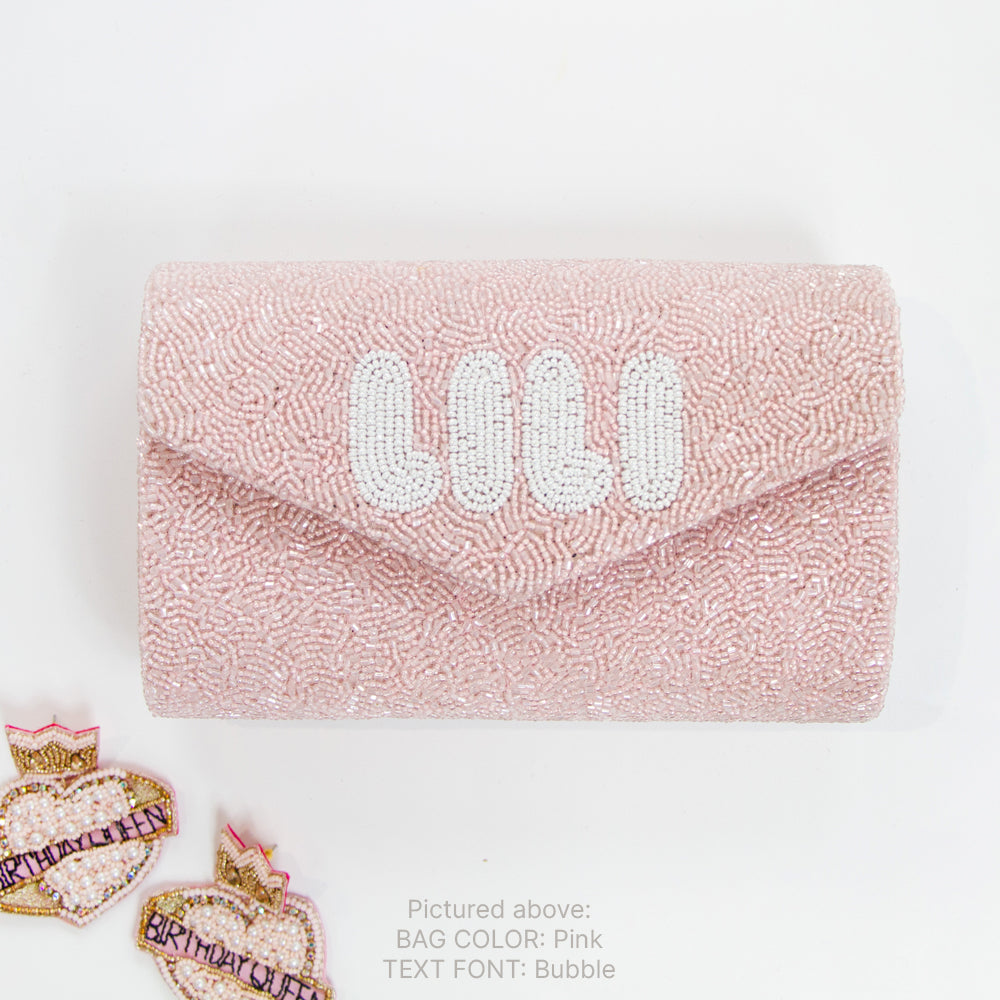 A pink handbag with the name "Lilly" printed on it, along with two heart-shaped badges with the text "Birthday Queen" on them.