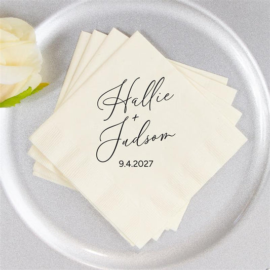 Stack of personalized napkins with names and date on a gray plate with a white rose.