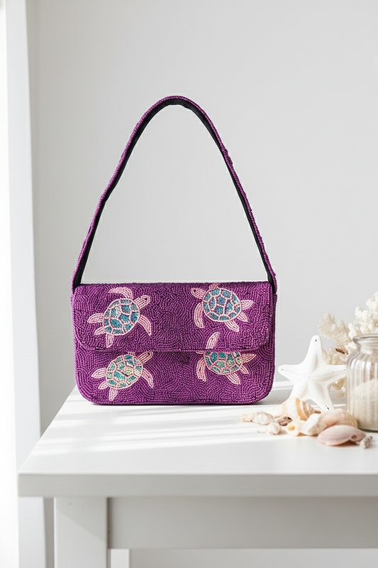 Purple handbag with turtle designs on a white surface