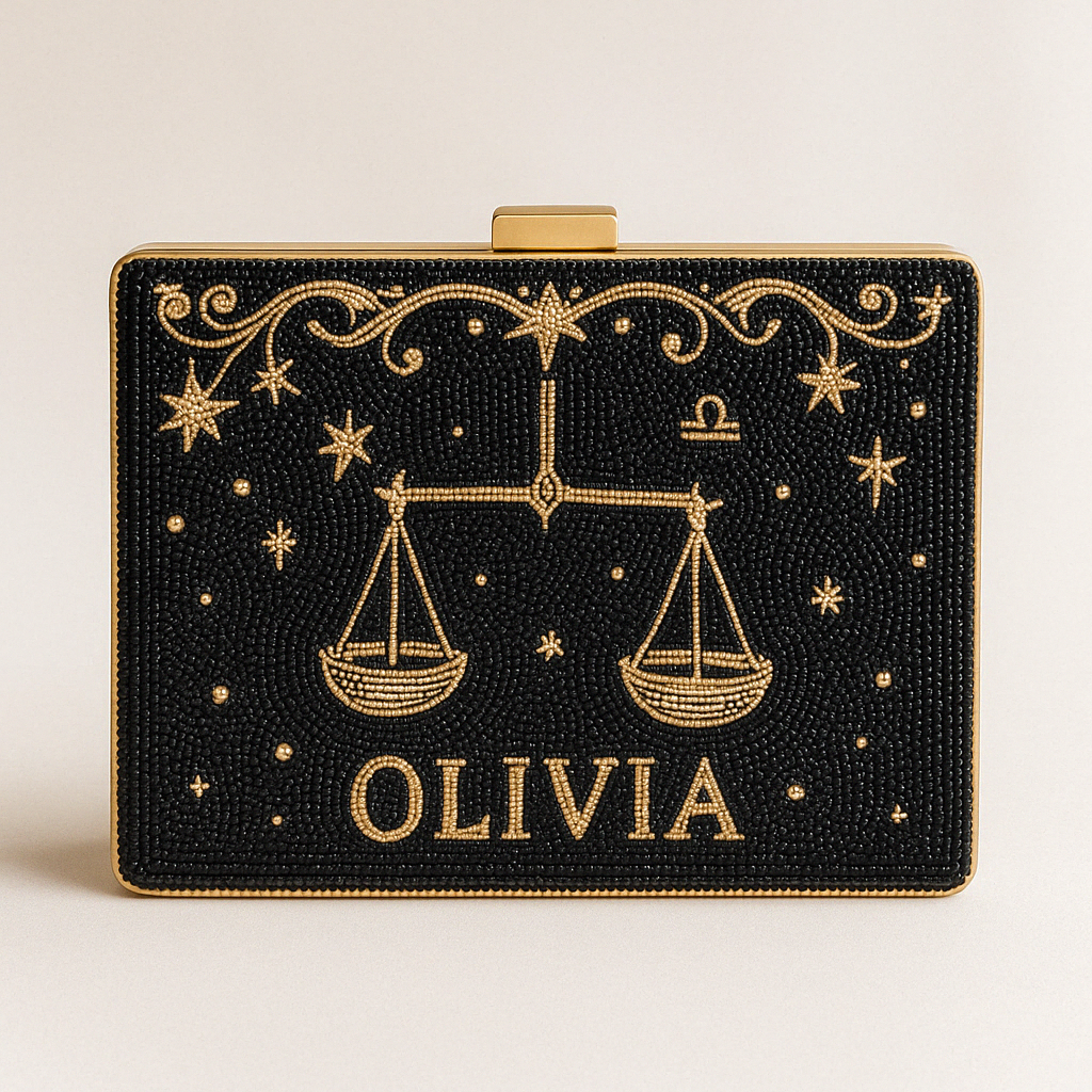A black clutch bag with gold embellishments, including a design of scales and stars, and the name "OLIVIA" printed on it.