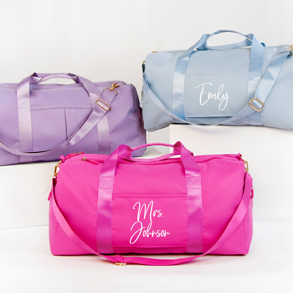 three colorful duffel bags, each with a personalized name printed on it.