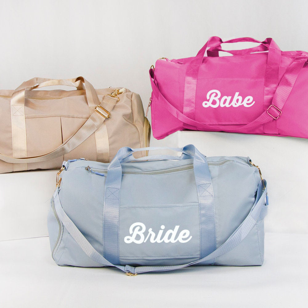 three colorful duffel bags, each with a different color and the word "Babe" printed on them.