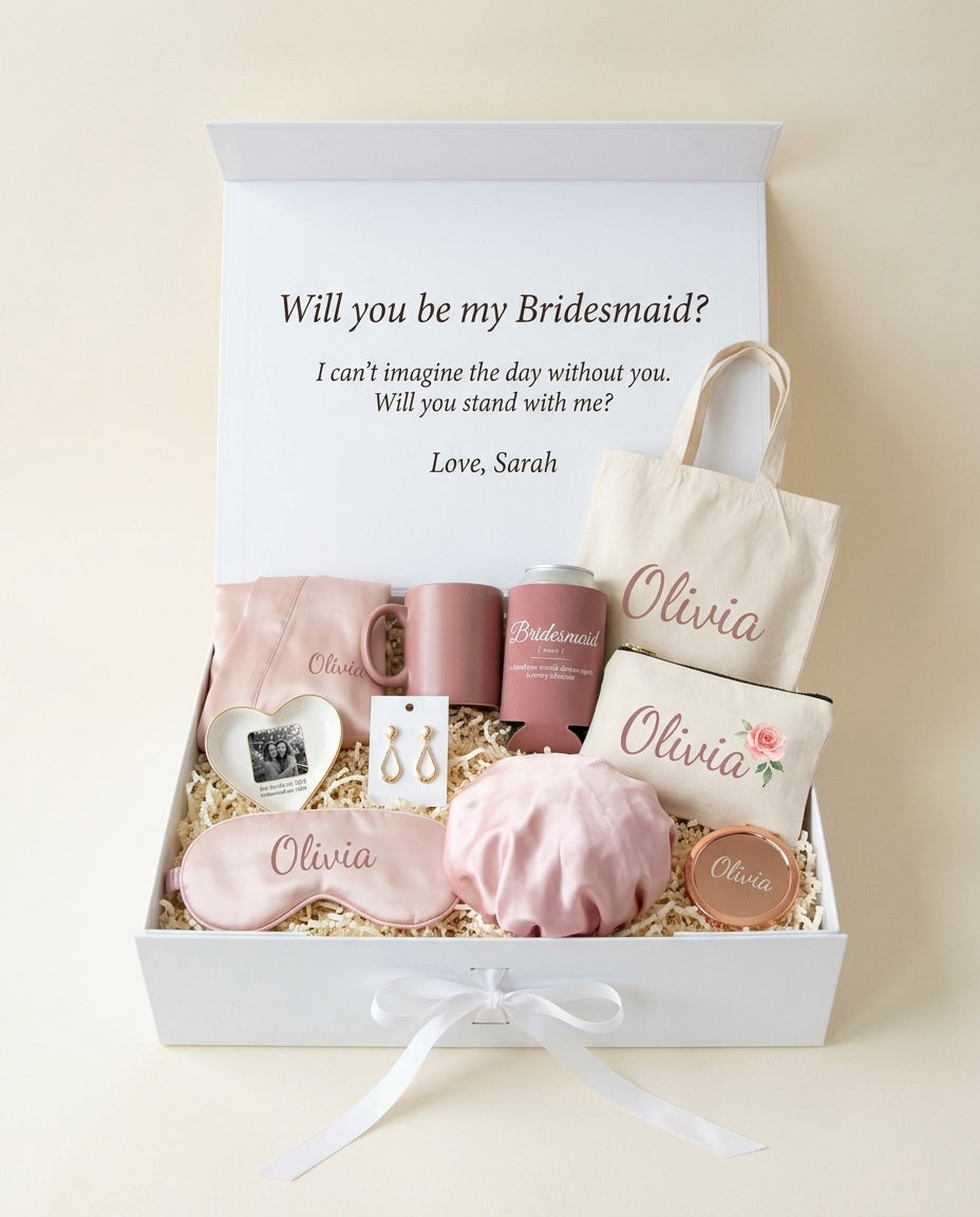 Getting Ready bridesmaid box open: letter printed inside the lid, satin robe, mug, photo trinket tray, eye mask and satin bonnet, bridesmaid earrings, Bridesmaid can cooler, canvas tote and makeup pouch with her name, rose gold mirror compact (render)