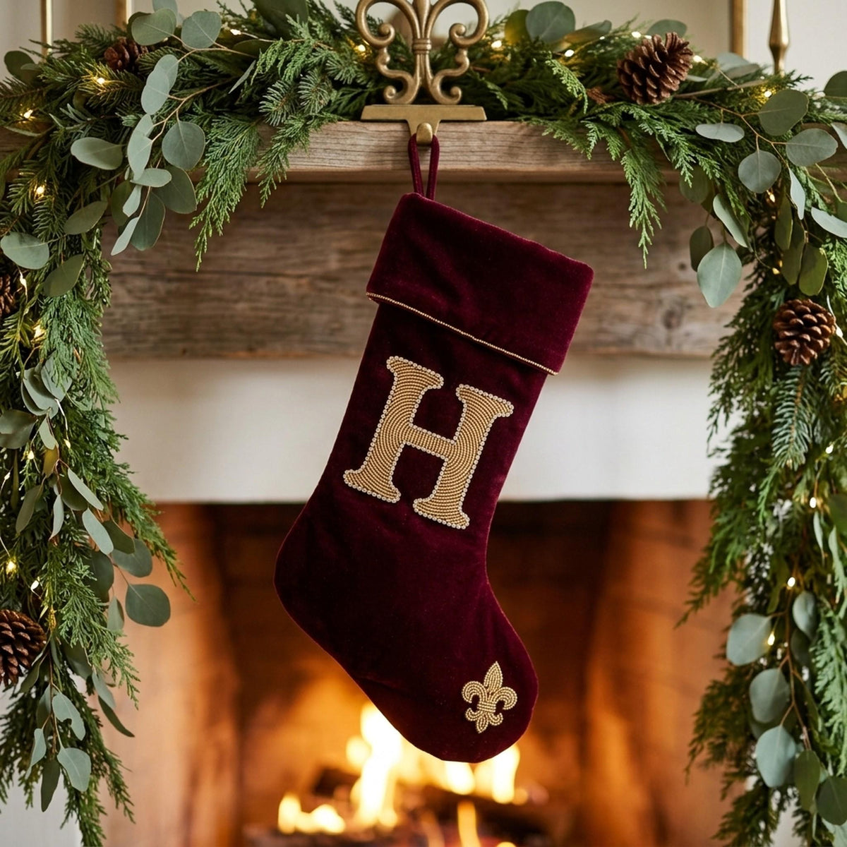 Oxblood velvet monogram stocking hanging on a mantel
