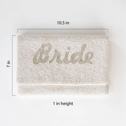White Bride Clutch Bag"Exquisite white beaded bridal clutch with silver 'Bride' text, handmade for perfection. This durable canvas clutch, sized at 10.5 x 7 x 1 inches, offers both elegance and functionality for the wedding day. Its unique design ensures a one-of-a-kind accessory for the bride."